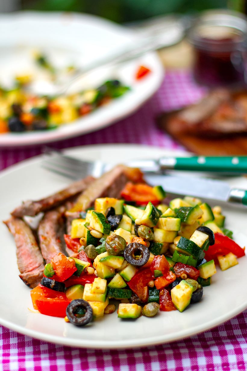Zucchini caponata salad with tomatoes, olives, capers and pine nuts