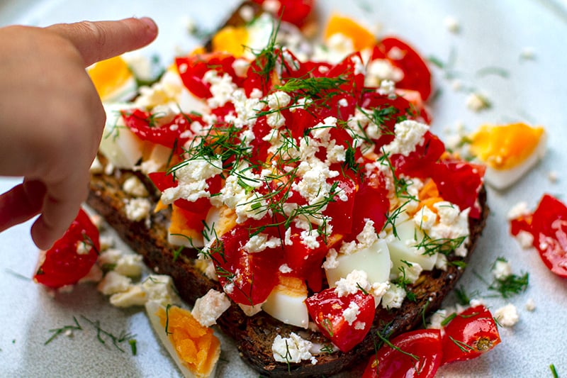 Boiled jammy eggs on toast with feta tomatoes and dill - landscape image of the recipe