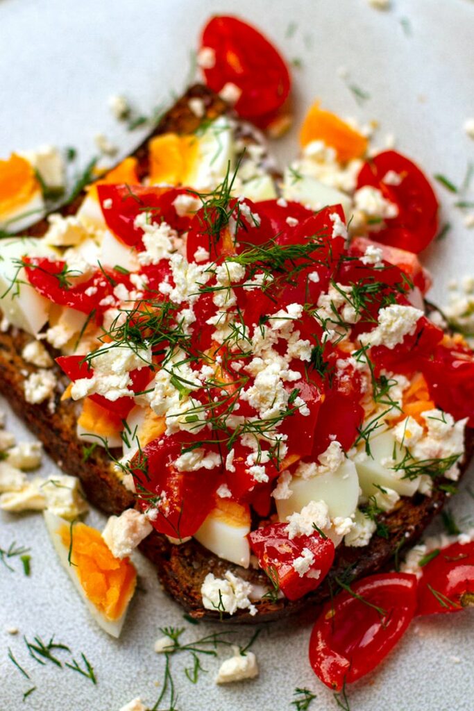 Jammy eggs on toast with tomatoes, feta and dill - side angle image